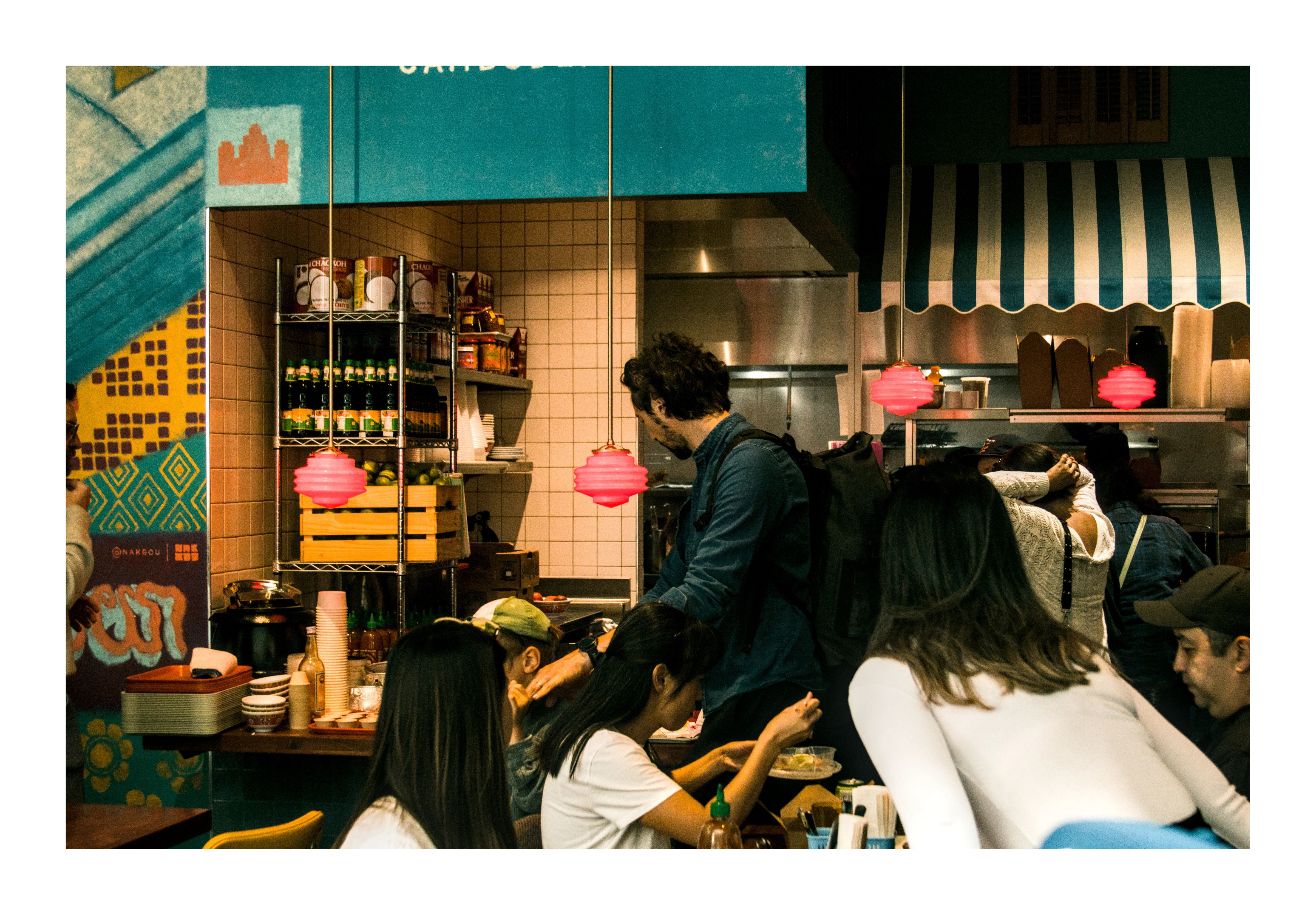 Diners gathered beneath red pendant lights at a food counter