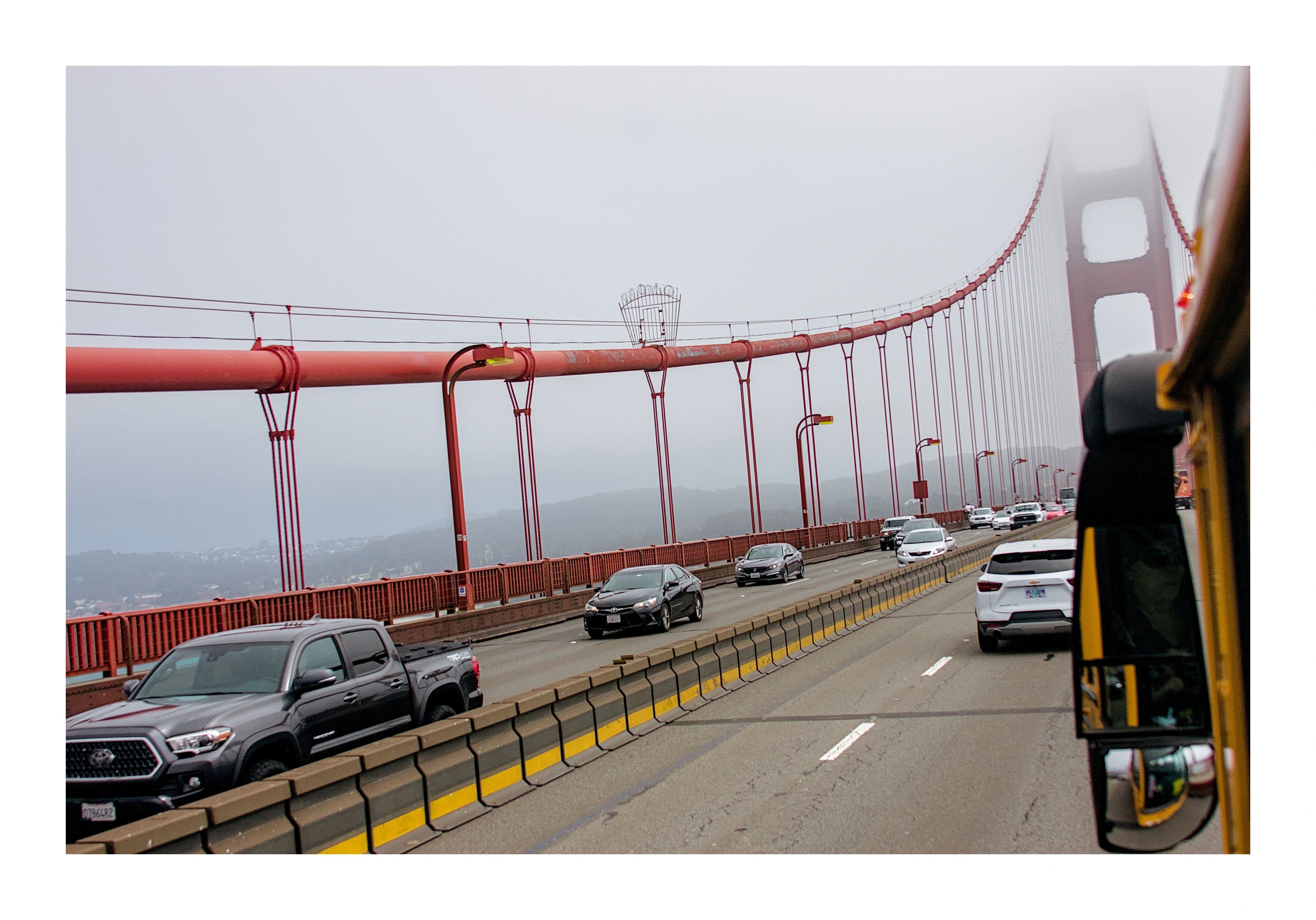 The Golden Gate Bridge disappearing into fog, seen from a bus