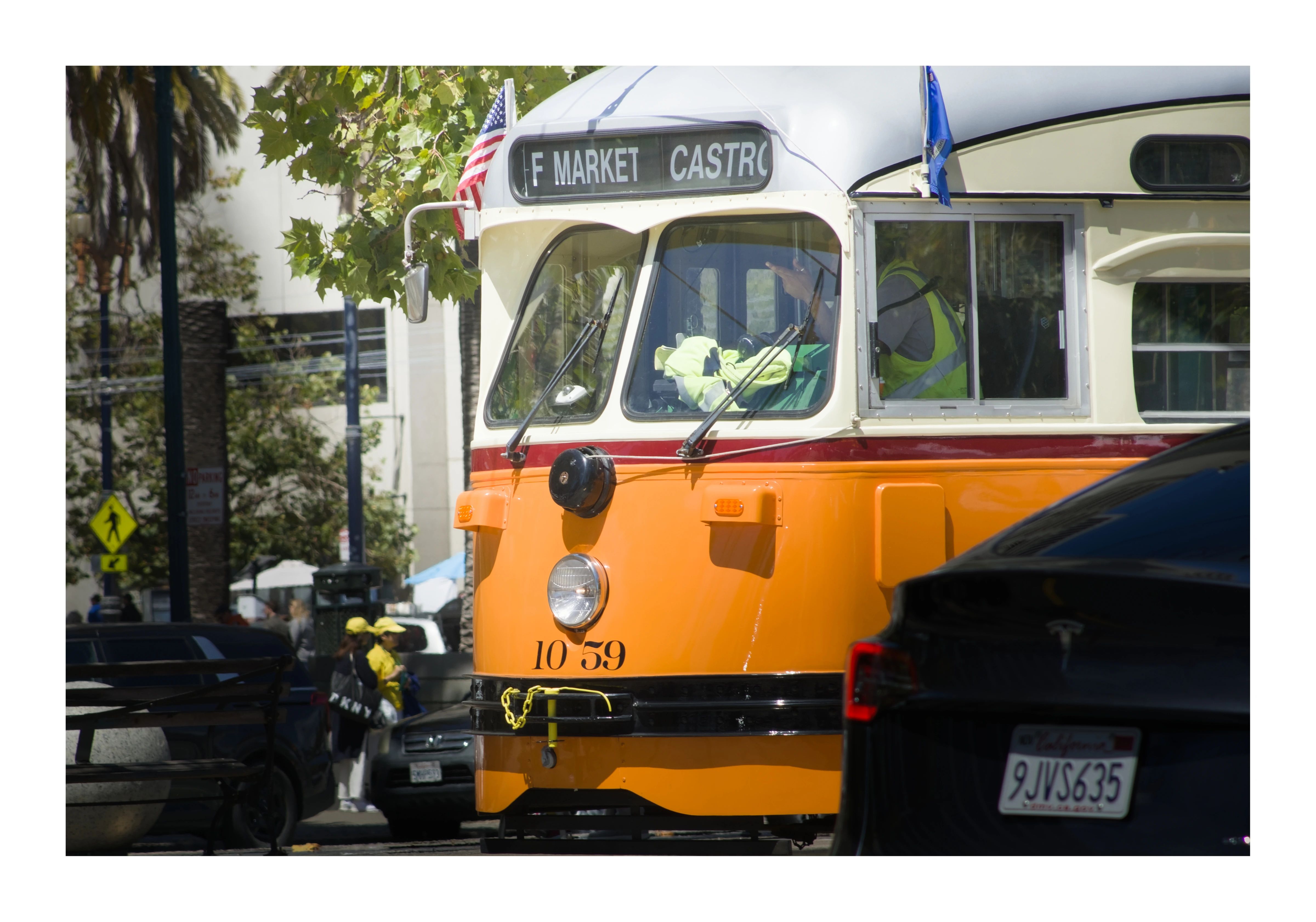 An orange historic streetcar waiting on Market Street