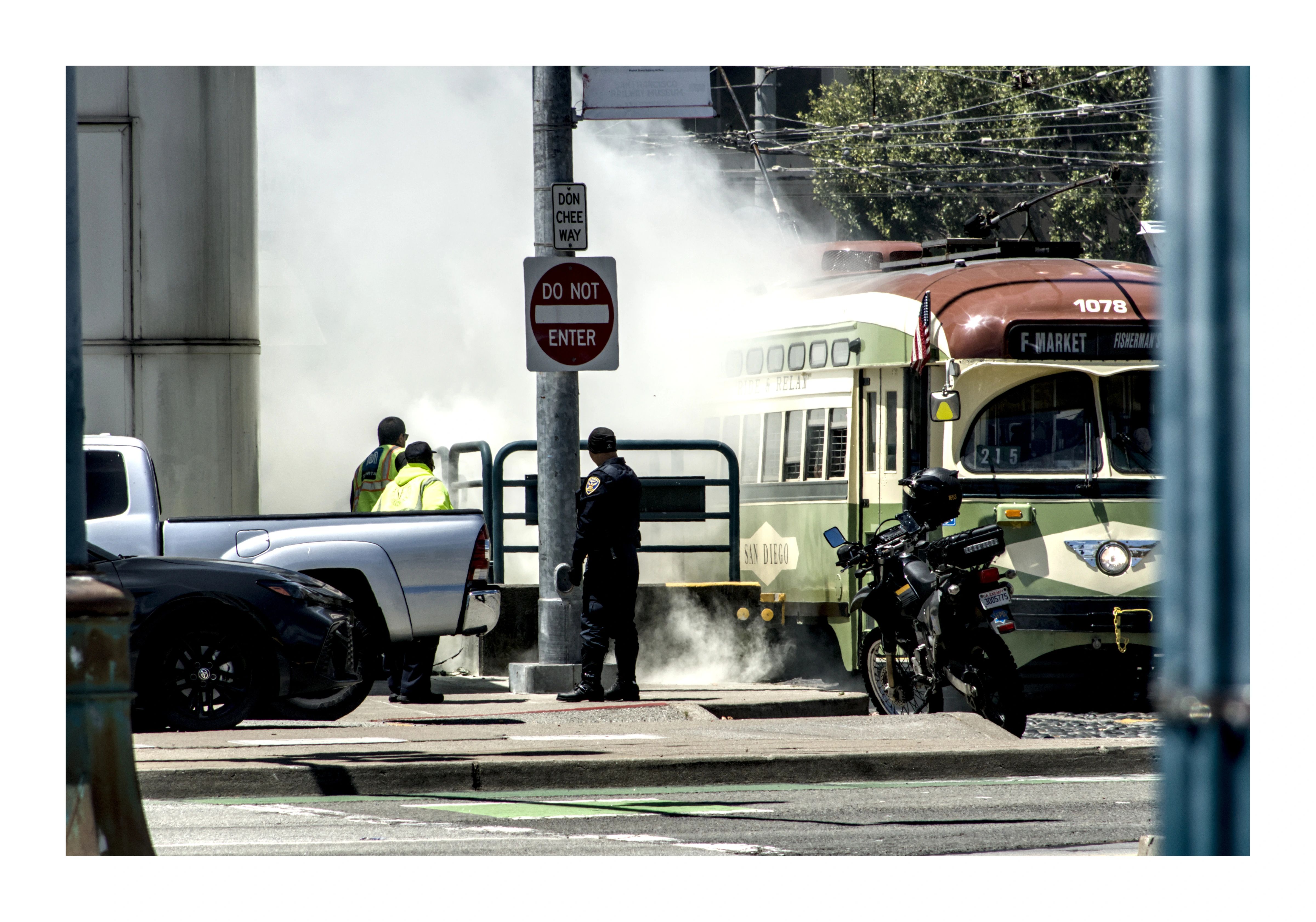 Steam rising around workers and a streetcar at an intersection