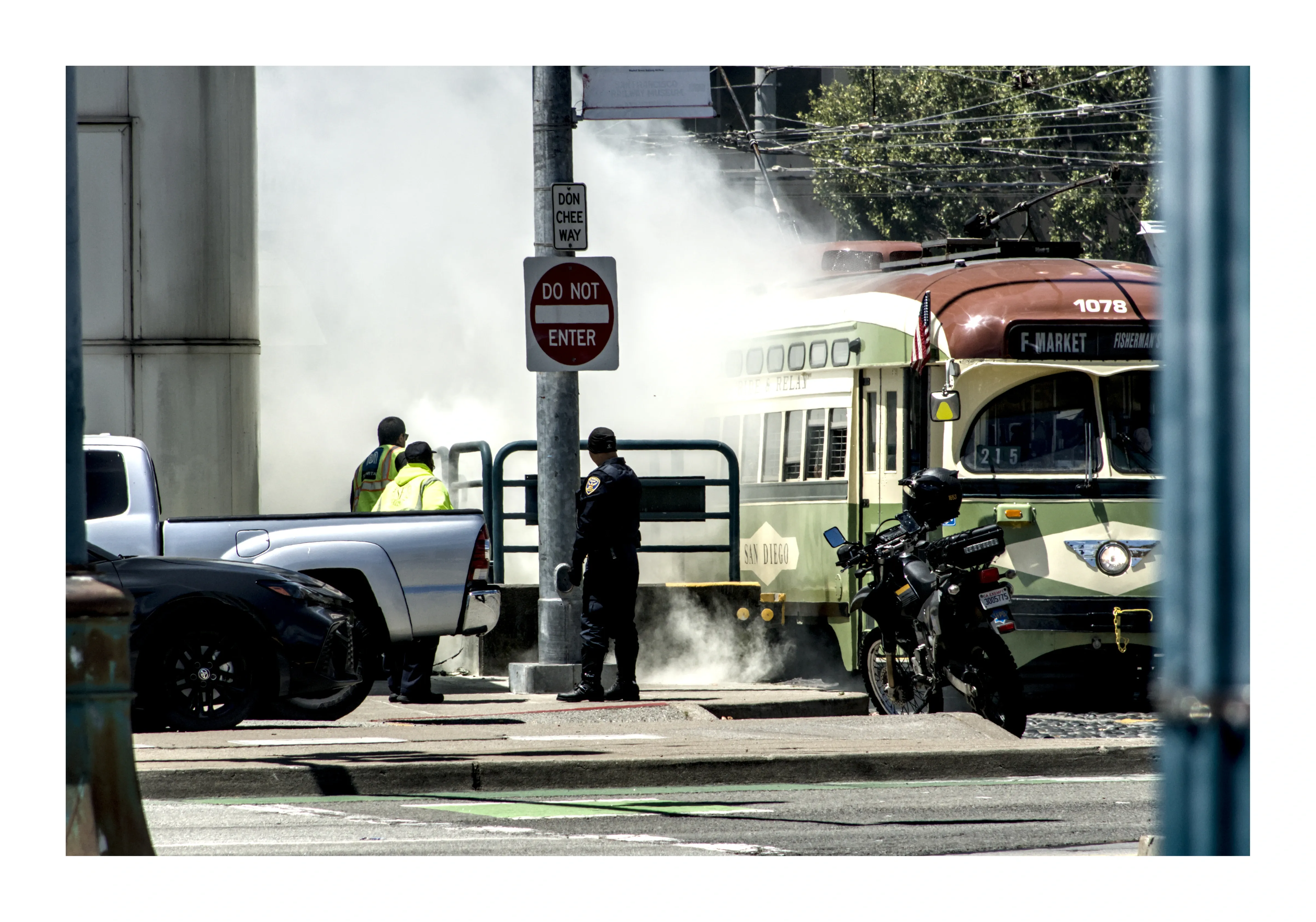 Steam rising around workers and a streetcar at an intersection
